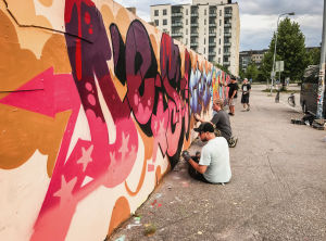 Täällä näkee usein samoja tuttuja kasvoja, pitkään graffiteja tehneitä tyyppejä, kertovat Klaus Barck ja Pasi Leppänen sekä taaempana maalaavat Hannu Vänskä ja Saku Kuusiola. Graffitiseinällä ihmisiä maalaamassa.