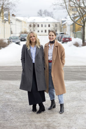 Du måste lite på dig själv och våga ta betalt för det du gör, säger Michelle och Sandra. Två kvinnor står ute på en gata. Michelle till vänster i bild har långt blont hår och grå kappa. Sandra till höger har håret i hästsvans och beige kappa. Båda ler.