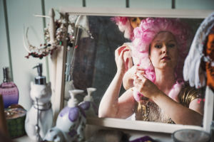 Pianisti Sonja Hendunen katsoo peiliin pinkki perukki päässä, taustalla laulaja Noora Määttä.
