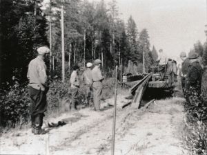 Mustavalkoisessa arkistokuvassa työmiehiä metsässä purkamassa junarataa.