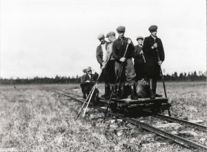 Mustavalkoisessa arkistokuvassa työmiehiä resiinan päällä kapearaiteisella raiteella.