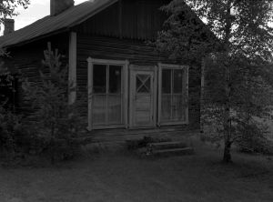 Aseman yhteydessä sijainnut vanha kaupparakennus kuvattuna 1980-luvulla. Mustavalkoisessa arkistokuvassa huonokuntoinen puutalo.