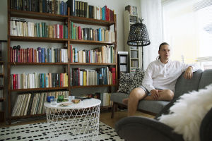 Kasper sitter i en soffa som står framför en stor bokhylla.