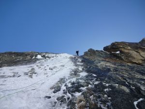 Ibland måste André ta hjälp av rep för att komma ner. En person står uppe på en bergstopp. Nedanför personen hänger ett rep. Hen ska snart börja gå ner för berget med hjälp av repet.