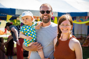 Perhe hymyilee kameralle Natural High Healing Festivalilla, nainen, mies, vauva