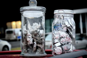 Felsorterat! Burken till vänster innehåller klimpar av aluminium som skrapats loss ur Westenergys panna. Folie och dryckesburkar är inte brännbart avfall. Klimpar av smält aluminium i en burk, samt burklock, ljuskoppar och aluminiumfolie i en burk