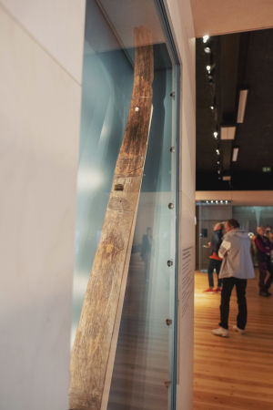 Reen jalas vitriinikaapissa, taustalla museossa vierailevia ihmisiä.