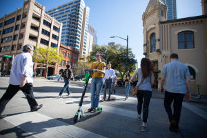 Fotgängare och en person med elektrisk sparkcykel som korsar en gata i Austin i Texas.