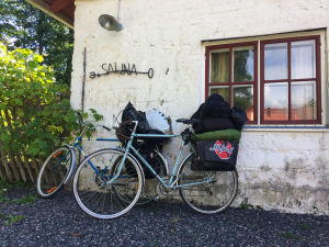 Pyörät nojaavat valkoiseen kiviseinään, jossa lukee sauna.