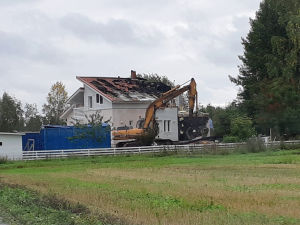 Grävmaskin framför det brandskadade huset.