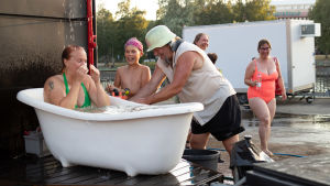 Äiti kylpee ja lapsi pumppaa suikusta vettä