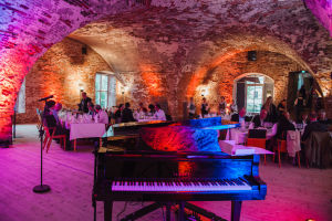 A grand piano in a lit vaulted ceiling restaurant. 