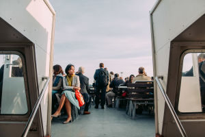 People sitting on the outside deck on a ferry.