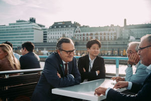 Four men engaged in a discussion over a table on the outside deck of a ferry outside Helsinki.