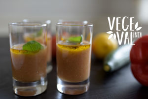 En vegetarisk gazpacho i glas. Bilden har kort skärpedjup men i bakgrunden kan man skönja en gurka och en citron. Högst uppe i höger hörn finns Vegval/Vegevalintas logotyp.
