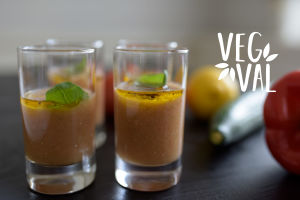 En vegetarisk gazpacho i glas. Bilden har kort skärpedjup men i bakgrunden kan man skönja en gurka och en citron. Högst uppe i höger hörn finns Vegval/Vegevalintas logotyp.