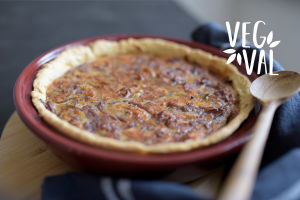 En vegetarisk lökpaj. Bilden har kortskärpedjup och högst uppe till höger finns Vegval/Vegevalintas logotyp.