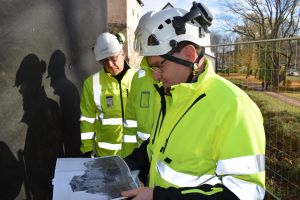 Tommi Vilkanen och Ari Leppäniemi undersöker ett foto som visar vilka skador Åbo slott fick under fortsättningskriget. Miehet katsovat Turun linnan pommituksia esittelevää kuvaa
