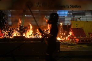 Demonstranterna brände upp en metroingång vid kampuset till Chinese University of Hong Kong. Person står vid en brinnande metrostation i Hongkong.