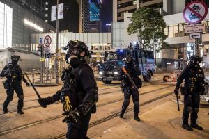 Kravallpolisen bevakar gatorna i centrala Hongkong efter att ha skingrat demonstranterna från området. Poliser med batonger på gata i Hongkong.