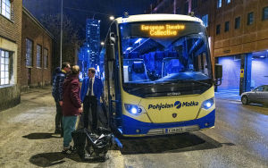 Miehet seisovat bussin vieressä.