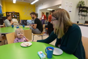 Marika Blomqvist sitter vid kaffebordet och äter mellanmål med dottern Olivia på öppna daghemmet Tallen på Drumsö i Helsingfors.