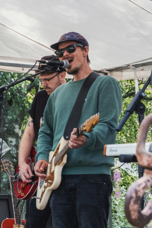 UGH-festareilla 2019 soitti Club De Lay. Kaksi miestä soittavat ulkoilmalavalla kitaraa, toinen laulaa mikrofoniin.