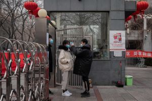En säkerhetsvakt mäter kroppstemperaturen hos en lokalinvånare på väg hem i huvudstaden Peking. Coronaviruset tros påverka tiotusentals kinesers liv. En vakt mäter kroppstemperaturen hos en kinesisk kvinna.