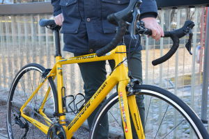 Den gula cykeln är lätt och väger endast ungefär åtta kilo. Närbild på en gul cykel.