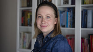 Porträttbild av Sandra Holmgård. Hon har blå skjorta och ett svart diadem.