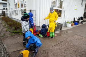 Barnen på daghemmet Grankotten har fullt upp med att tömma den stora pölen på gården. Lastentarha Grankotten kauniainen.