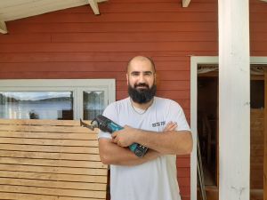 Västnyländska byggföretagaren Mufid Azad har nu jobb flera månader framåt. Man med ett sågverktyg i handen framför en rödmålad vägg.