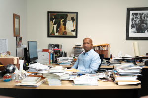 Bryan Stevenson. Bryan Stevenson sitter vid sitt arbetsbord, omringad av pappershögar och böcker.