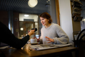 Svenska Yle träffar Iiris Viljanen på ett folktomt kafé i Finntorp. Iiris Viljanen vid ett kafébord.
