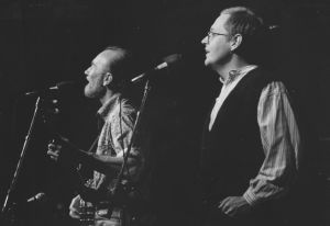 Pete Seeger ja Mikko Perkoila kuvattuna Vanhan ylioppilastalon lavalla kesken lauluesityksen.