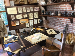 Leonardo da Vincin työhuone: kirjoituspöydällä papereita, piirustusvälineitä, seinällä luonnoksia.