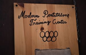 Den hemgjorda skylten på väggen i garaget fick av misstag två OS-ringar för mycket. Skylt med texten Modern Pentathlon Training Center, som hänger på väggen hemma hos femkampsfamiljen Salminen.
