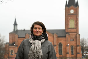 Lilian Järvinen är ny kulturturismkoordinator vid Lovisa stad. Här står hon vid en promenadrutt som börjar vid Lovisa kyrka - rutter med infotavlor hör enligt henne till kulturturismen. En kvinna står framför Lovisa kyrka.