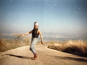 Taustalla Jordan Valley Israelissa. Pia Lindy työskenteli koko talven maatilalla poimien mangoja, ruusuja ja tomaatteja. Kuva on noin vuosilta 1988–89. Pia Lindy tanssii tiellä, joka on korkean vuoren laella, taustalla Jordan Valley.