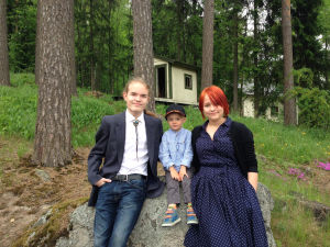 Saalas, Elias ja Juno Ruokangas istuvat suurella kivellä metsäisen rinteen edustalla.