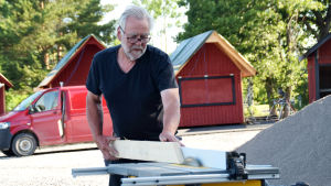 En man vid namn Mårten Johansson står och sågar en bräda vid en maskin. 