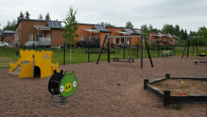 Lekparken i Alkrog är relativt ny och ligger intill bostadsområdet. En park med gult slott att rutscha ner för, sandlåda, fjädergunga och nya radhus i bakgrunden.