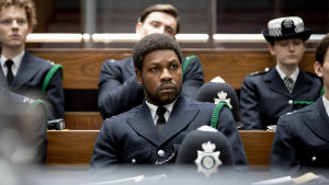 Konstaapeli Leroy Logan (John Boyega) istuu uniformupukuisena muiden poliisien joukossa luentosalissa. Kuva elokuvasta Small Axe: Red, White and Blue
