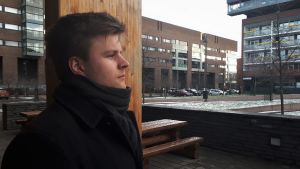 Anders Westerlund var också själv till en början skeptiskt till yrket. Hans fördomar försvann efter att han provat på att jobba som personlig assistent. En man står framför en träpelare med höghus i bakgrunden.