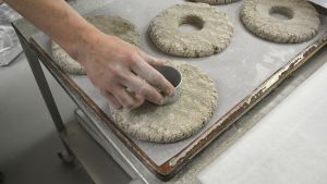 Bageriets populäraste bröd är hålkakan som består av endast råg, vatten och salt. Händer trycker ut mitten av rågbrödet med en mettalform.