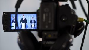 En kamera filmar försvarsminister Jussi Niinistö som håller presskonferens.
