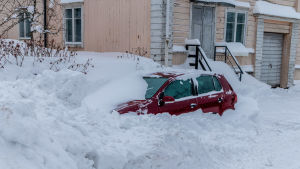 Här gömmer sig en bil. Det behövs mer än några spadtag för att komma iväg. Insnöad bil i snöhög.