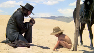 Mies mustissa ja alaston pikkupoika hiekka-aavikolla. Kuva elokuvasta El Topo.