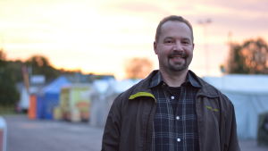Werner Orre Man står på en marknadsplats, solen håller på att gå upp.