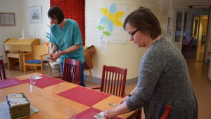 Jenny Sandström och Petra Henriksson tycker mycket om att jobba vid Solglimten. Två personer lägger ut bestick i matsalen i äldreboendet solglimten.
